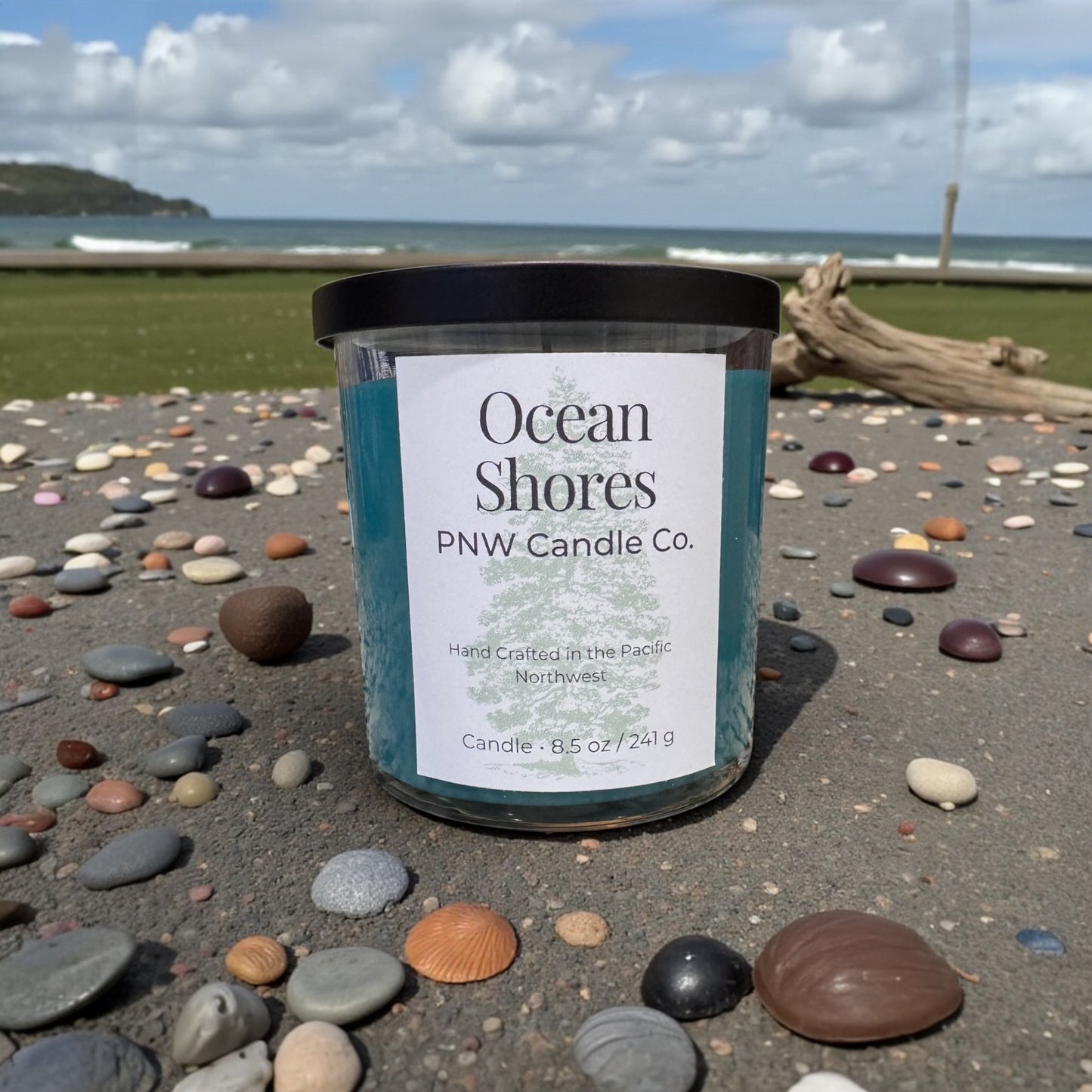 PNW Candle Co Ocean Shores scented candle in a glass jar with a natural beige wax and a burning wick, scented with ocean-inspired fragrances.