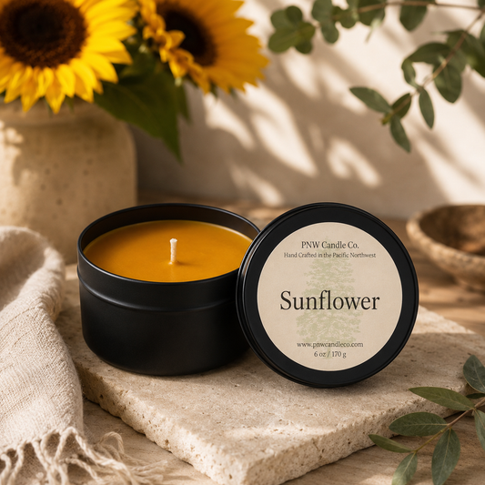 Sunflower scented candle by PNW Candle Co, featuring a glass jar with a lit wick and bright sunflower design.