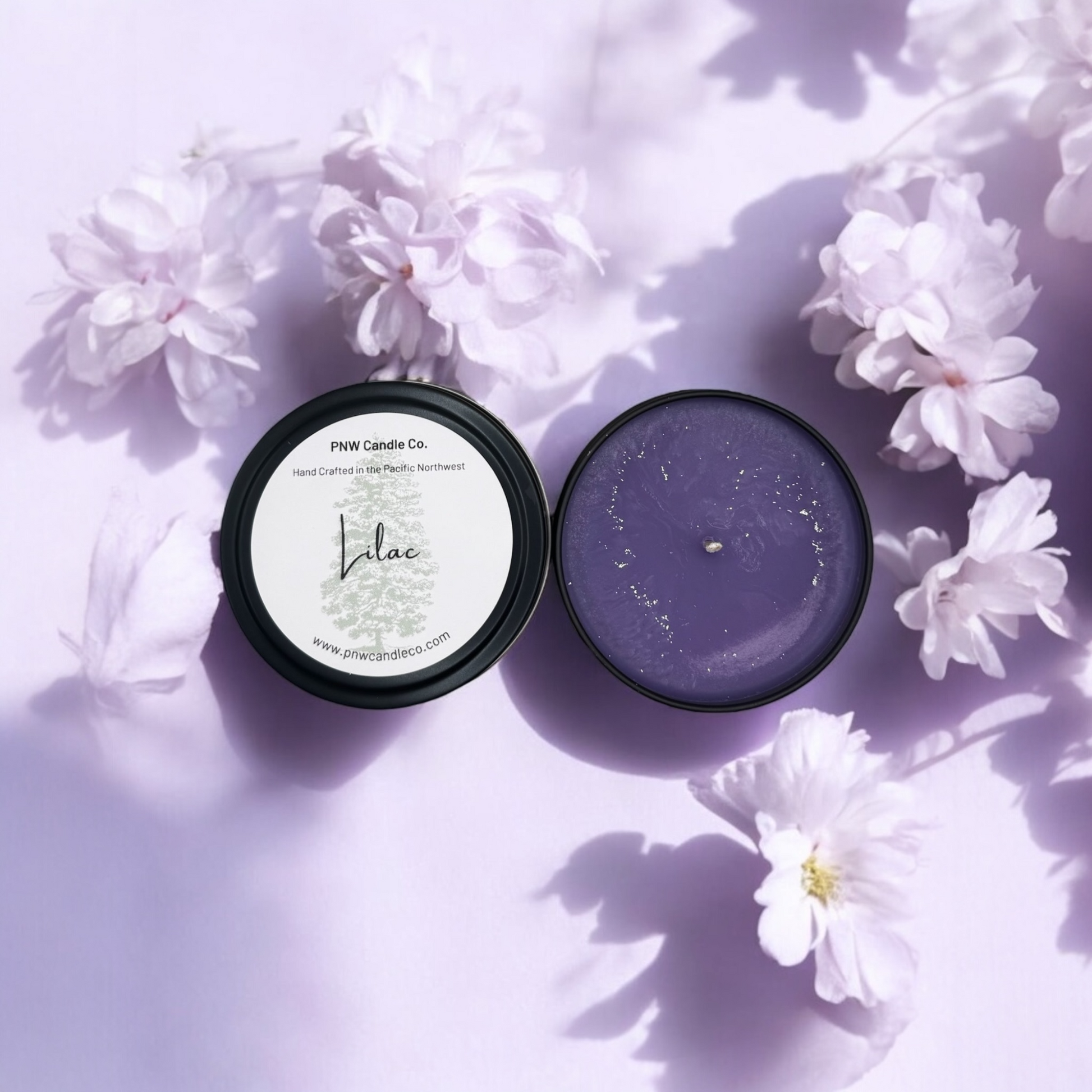 Lilac scented candle from PNW Candle Co with a white ceramic container and a lit wick, emitting a soft, floral glow.